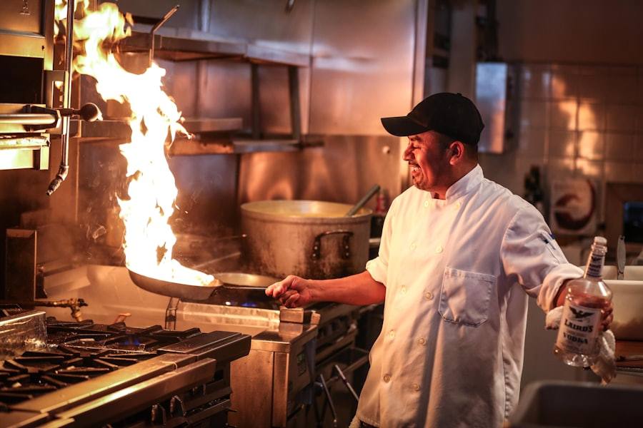 A chef at work over a flaming pan in a professional kitchen