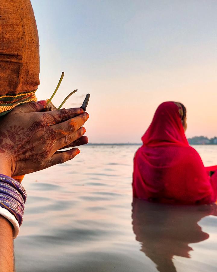Devotee offering arghya in the river at dusk during Chhath