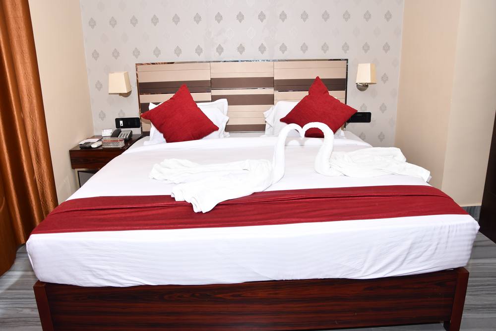 Deluxe Suite at Chinmaye Inn — king bed dressed with towel swans